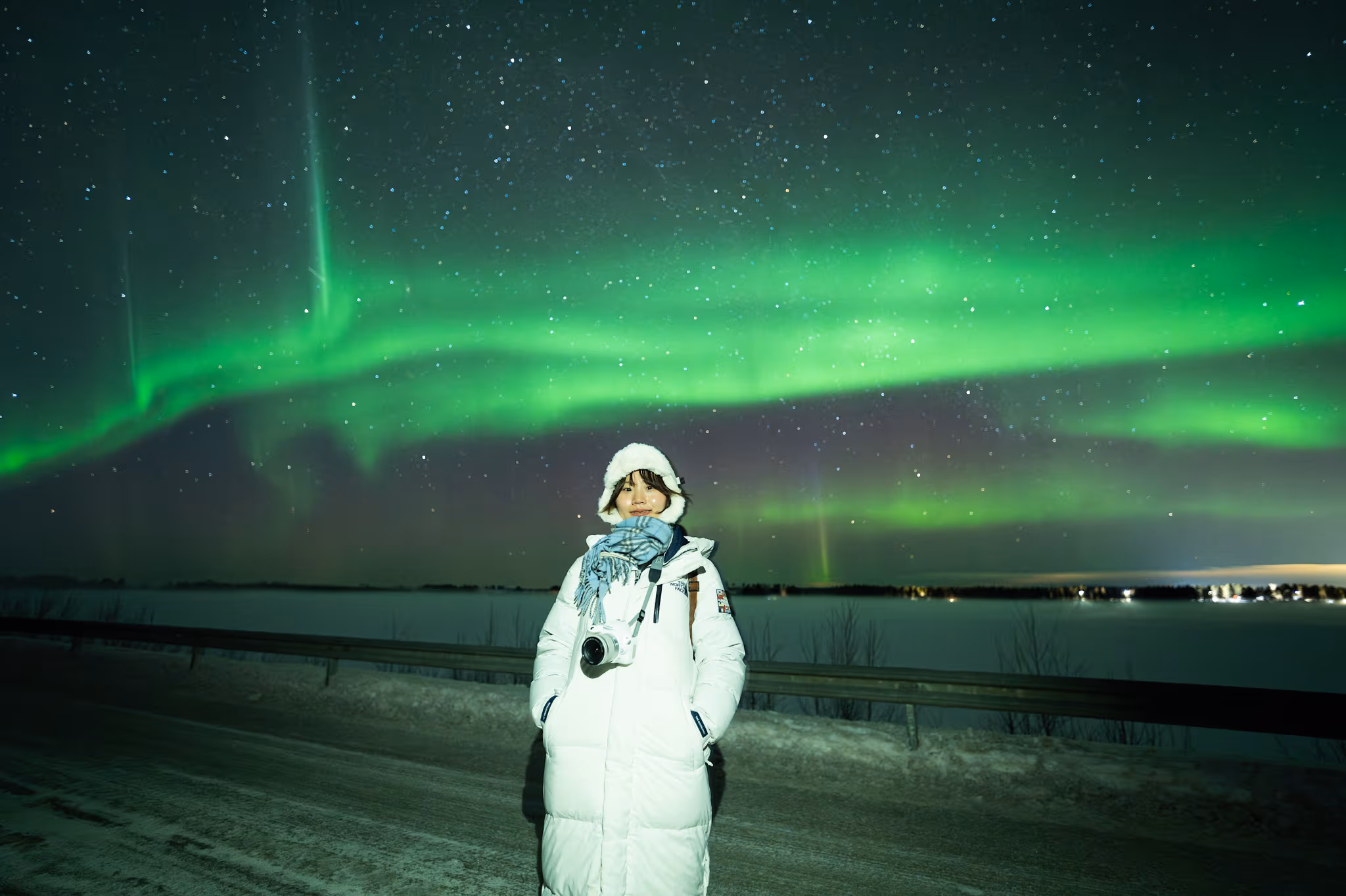 Guest in a white coat beneath green aurora