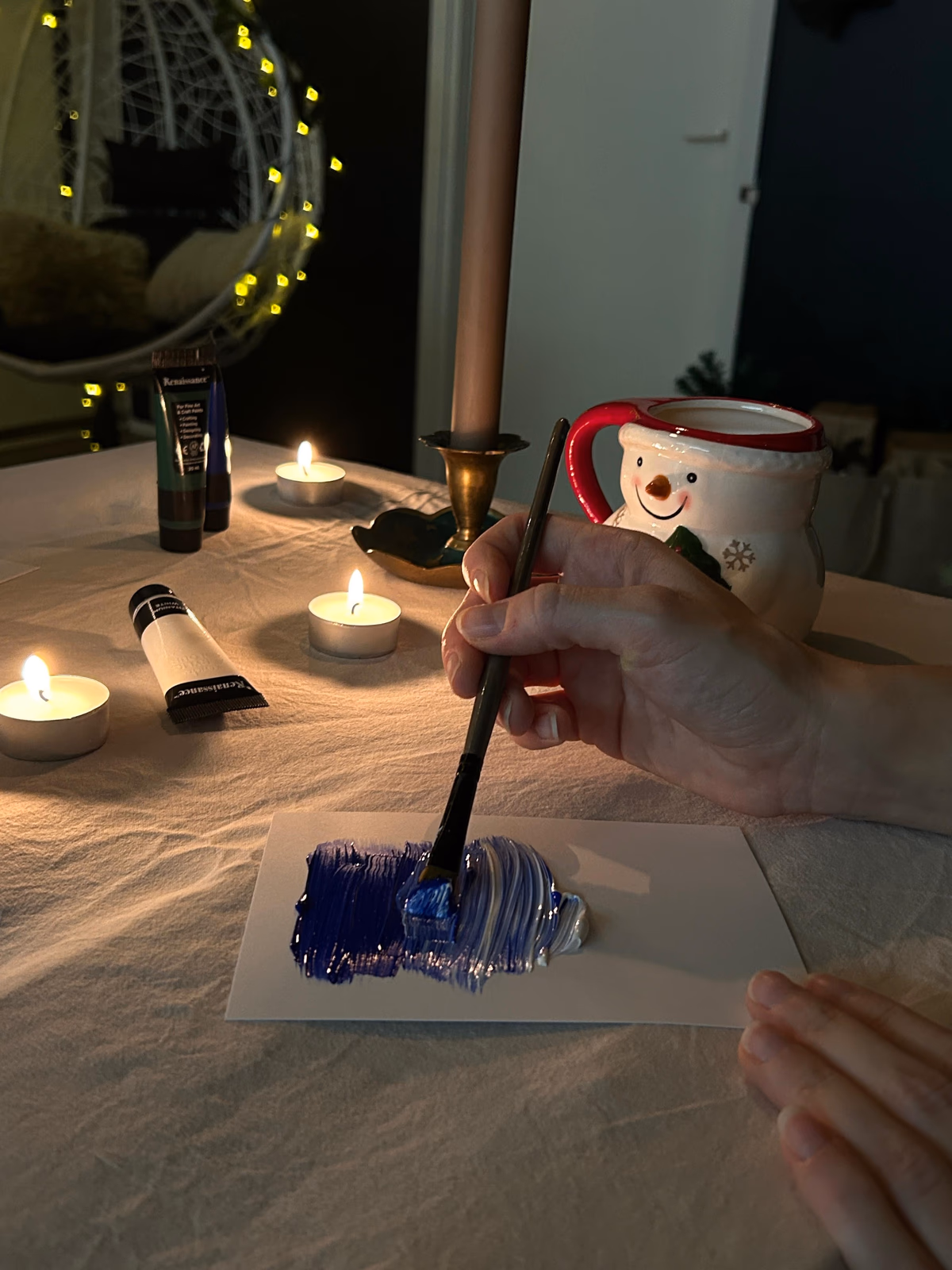 Painting a blue background on a postcard at the Rovaniemi workshop